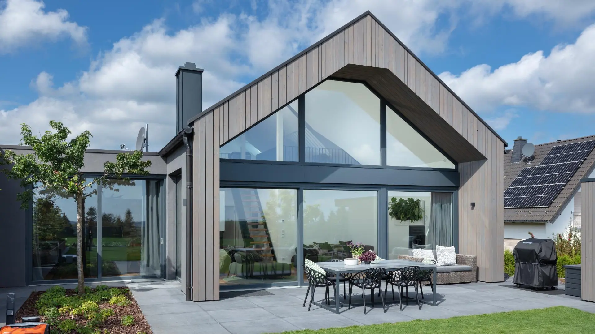 Modernes Wohnhaus mit großflächiger, individuell geformter Fensterfront im Giebel