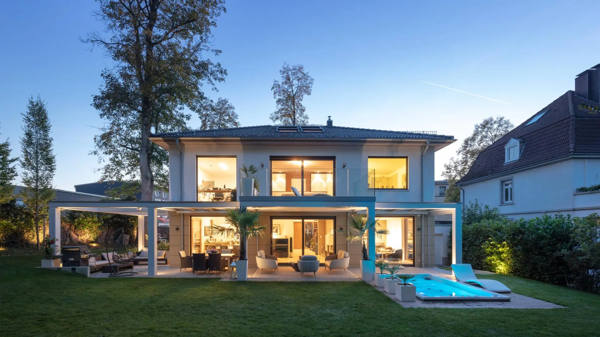 Modernes Wohnhaus mit großflächigen Holz-Aluminium-Fenstern bei Abendlicht