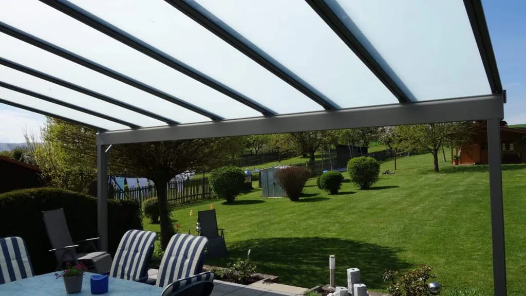 Schlanke Aluminiumprofile und Glaseindeckung eines Terrassendachs über einem Sitzplatz