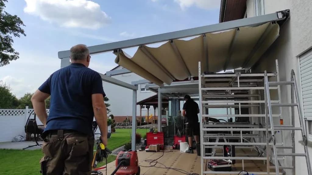 Zwei Monteure beim Aufbau eines Terrassendachs an einem Wohnhaus