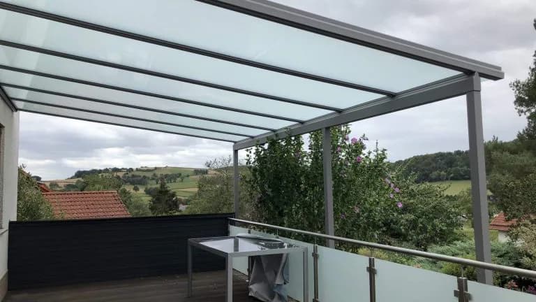 Fest mit einem Wohnhaus verbundenes Aluminium-Glasdach über einer erhöhten Terrasse