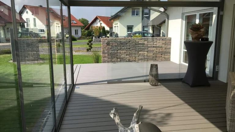 Terrassendach mit geschlossenen Glasschiebewänden und geschütztem Sitzbereich