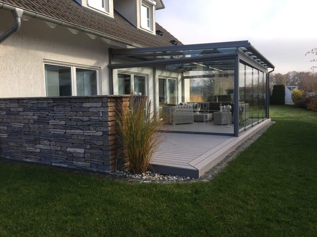 Aluminium-Terrassendach mit Glasdach und umlaufenden Glasschiebeanlagen an einem Wohnhaus